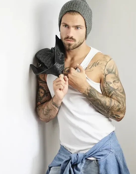 Homme tatoué avec un chapeau gris.